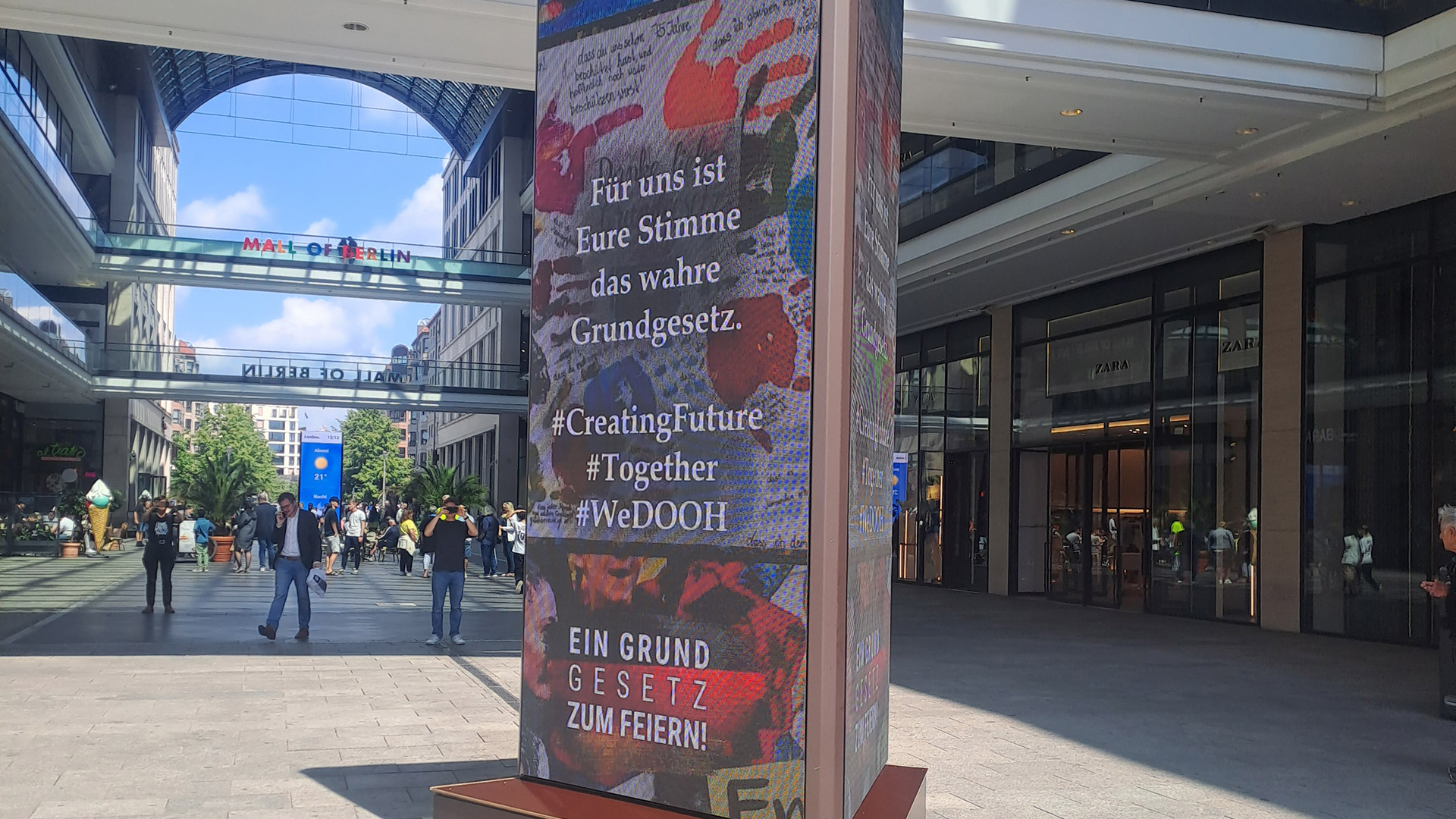 Säule mit buntem Collagenmuster und Text vor dem modernen Einkaufszentrum Mall of Berlin