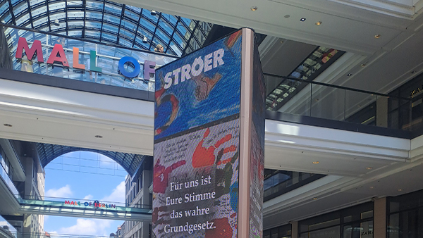 Ein moderner Einkaufspassagenbereich mit Glasdach und buntem digitalen Infoscreen