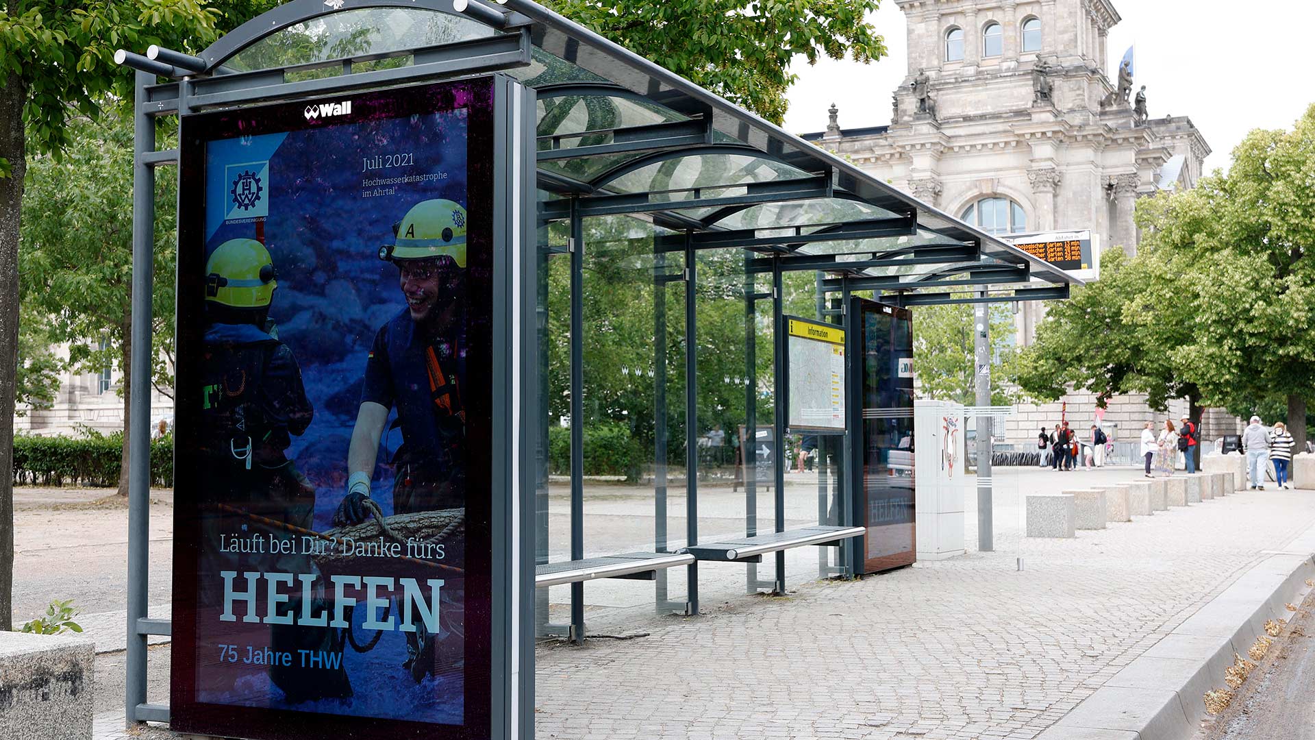 Zwei Personen in blauer Schutzkleidung und gelben Helmen lächeln nebeneinander